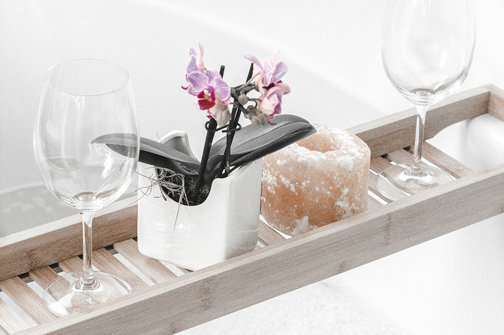 At-home spa day - bath tray with candle, orchid and wine glasses.