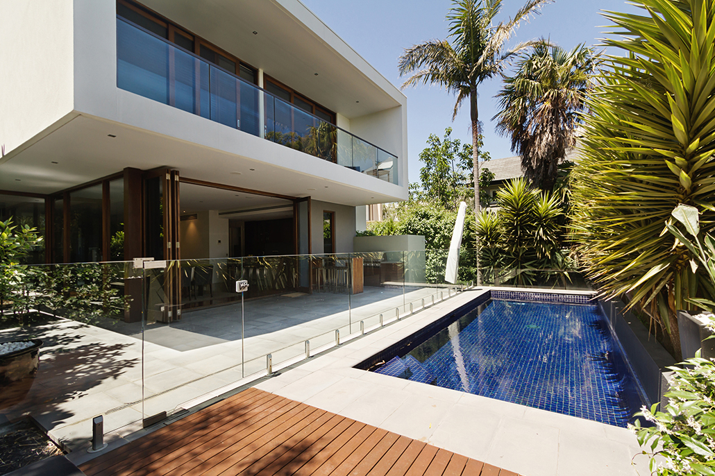 Exterior view of a contemporary Mater Lotteries prize home at dusk with landscaped gardens and warm interior lighting.