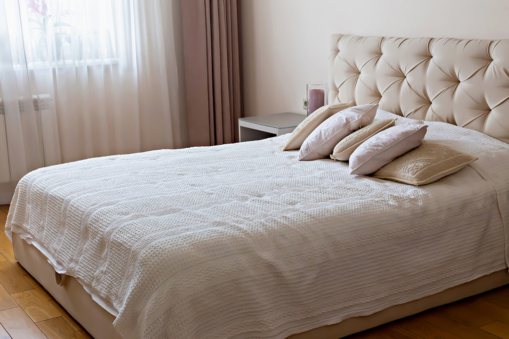 Townhouse Living: Minimalist bedroom with soft neutral bedding and natural light in a small apartment
