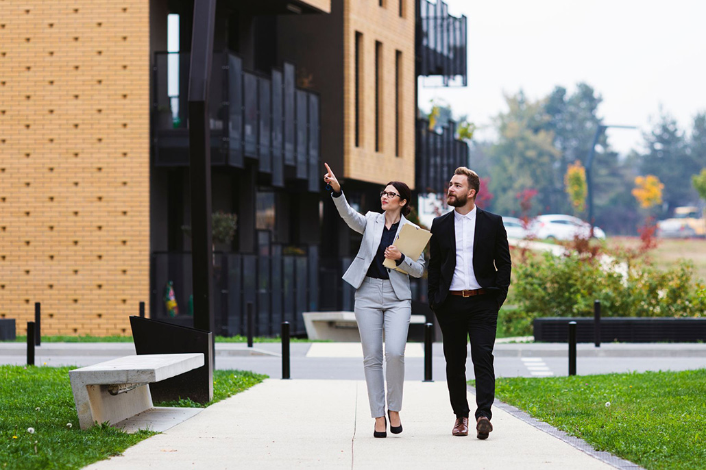 A prospective buyer inspects a modern townhouse complex with a real estate agent.