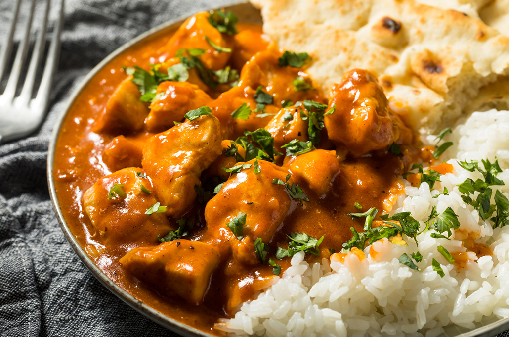 Butter chicken served with rice and naan on a dinner plate