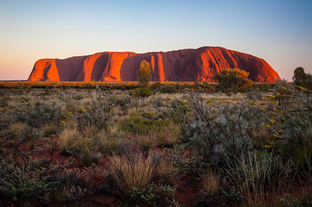 Explore Travel: Uluru illuminated by sunrise light in the Red Centre of Australia's Northern Territory.