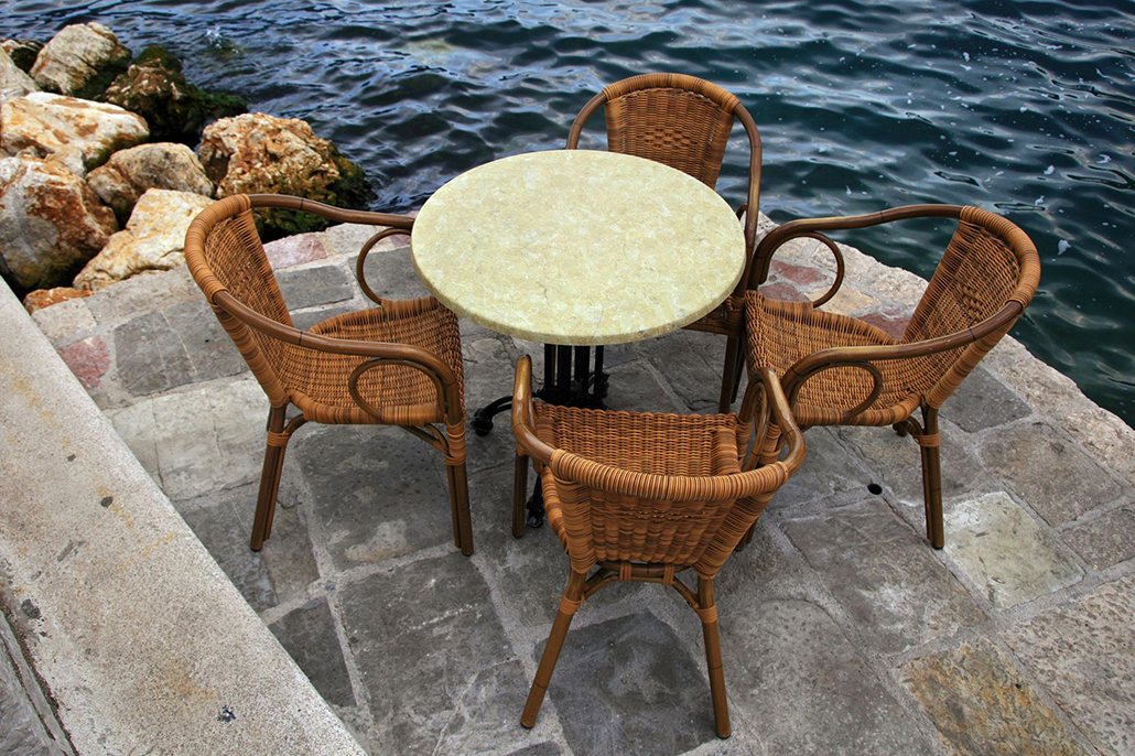 Woven outdoor chairs and stone table beside the water